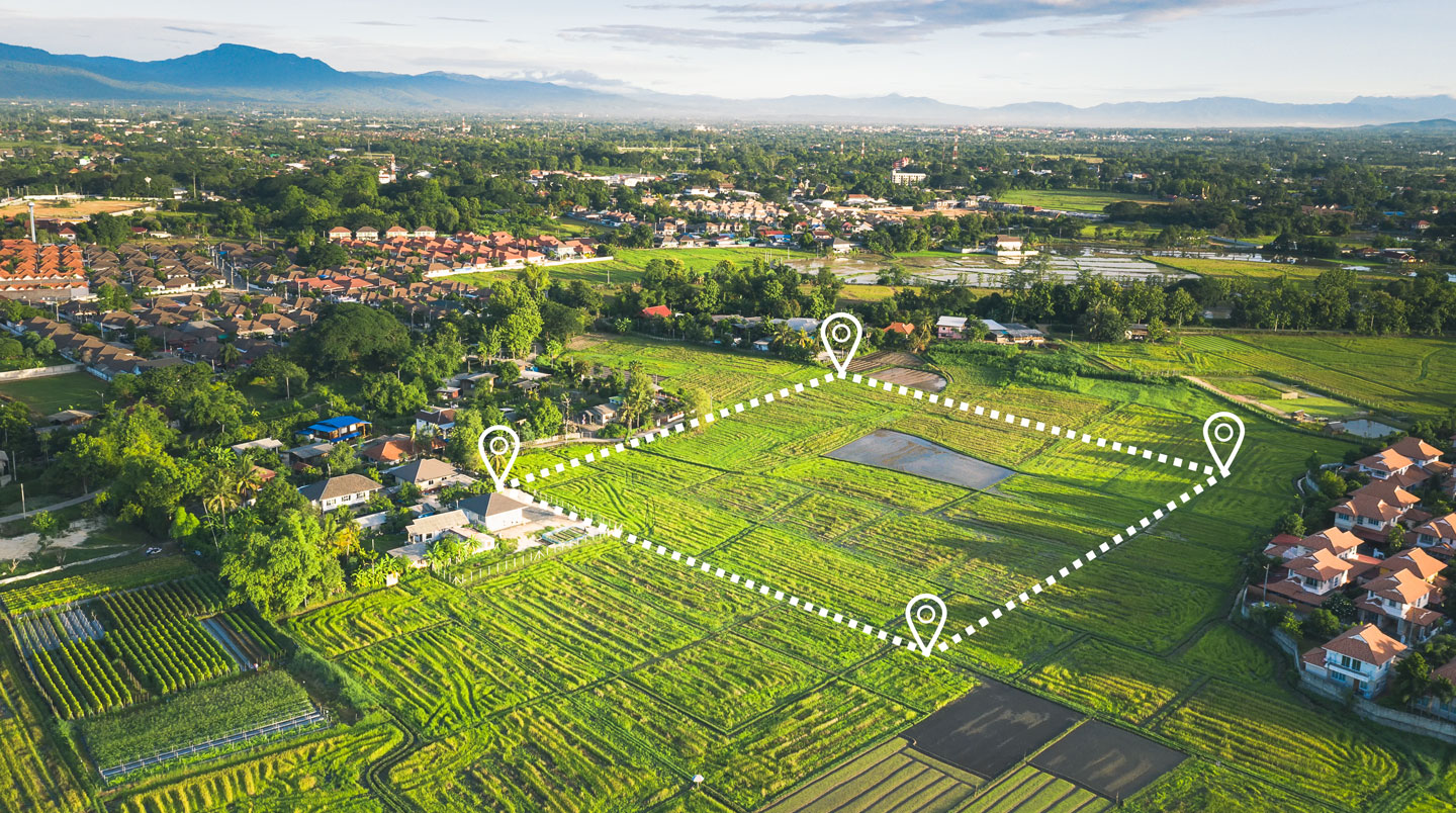 Parcelle de terrain constructible viabilisée à Bergerac délimitée par des bornes géomètre, avec panneau de vente et maisons résidentielles en arrière-plan